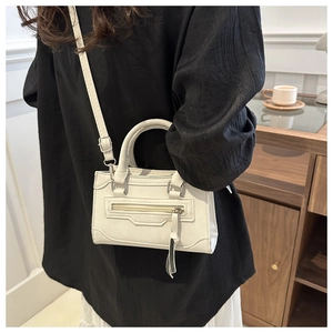 Détail d'un mini sac carré blanc crème montrant la sangle réglable et les ferrures argent