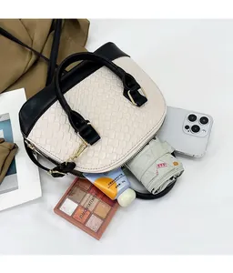 Détail du sac coquille bicolore montrant l'intérieur spacieux avec des accessoires