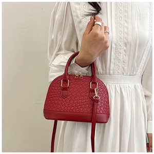 Détail du sac coquillage rouge avec texture tressée et finitions métalliques dorées