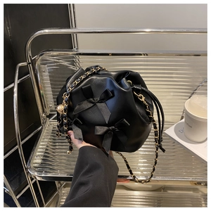 Détail du sac seau noir à nœuds avec fermeture à cordon et bandoulière chaîne
