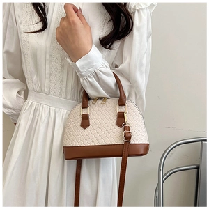 Vue détaillée du sac bandoulière tissé beige avec finitions en cuir marron et boucles dorées