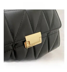 Detail of elegant black quilted leather bag with a luxury gold rectangular metal clasp