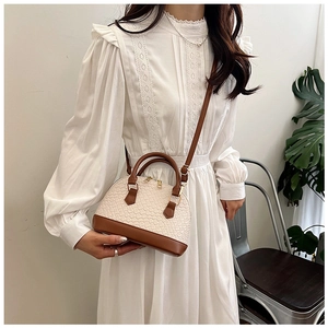 Sac bandoulière chic en forme de coquille avec texture tissée beige et détails en cuir brun