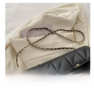 Detailed view of black quilted leather crossbody bag with golden metal clasp and chain strap