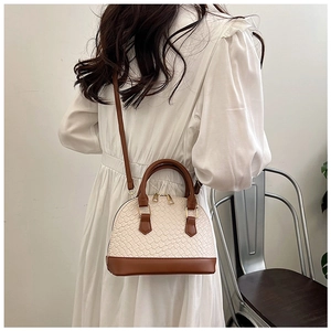 Sac coquille tressé crème chic avec lanières en cuir marron porté par un mannequin