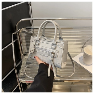 Détail du mini sac bandoulière gris clair avec poignée cylindrique et texture douce