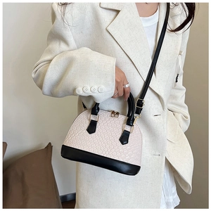 Vue détaillée du sac à main tissé crème avec finitions noires et détails dorés chic