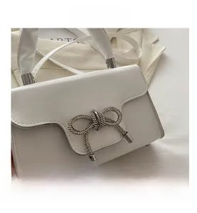 Detailansicht der weißen Ledertasche mit glitzernder Kristallschleife und Silbergriff