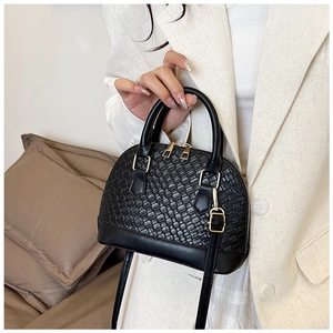 Détail du sac coquille noir tissé avec ferrures dorées et bandoulière réglable pratique
