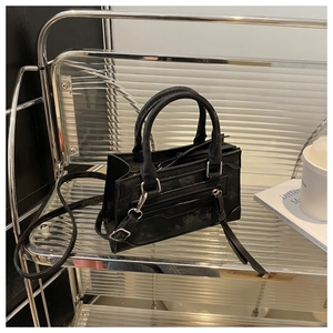 Détail d'un sac bandoulière noir vintage avec fermetures éclair sur support acrylique