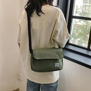 Dark green canvas messenger bag with adjustable strap and minimalist brand patch