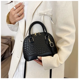 Détail du sac bandoulière noir en forme de coquille avec texture tissée chic