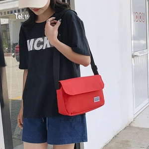 Japanese style minimalist red crossbody bag with adjustable wide black strap on street model