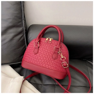 Gros plan du sac à main rouge en forme de coquille avec texture tissée sur canapé en cuir