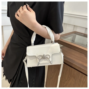Detail der weißen Ledertasche mit Strass-Schleife und elegantem geschwungenem Design