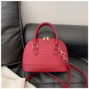 Détail du sac à main rouge avec texture tissée et fermeture à double glissière dorée