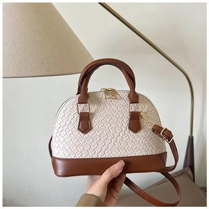 Gros plan détaillé du sac à bandoulière en forme de coquille avec texture beige tissée