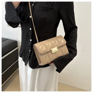 Detail of beige quilted leather chain bag showing gold metal clasp and cross body fit