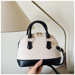 Détail du sac coquille en cuir tressé noir et blanc avec ferrures dorées élégantes