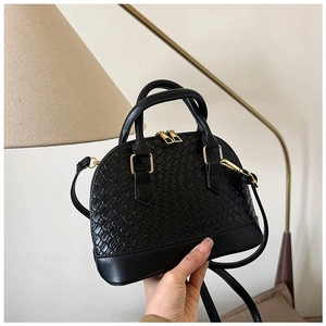 Détail du sac coquille tissé noir avec une texture raffinée et des finitions dorées