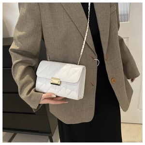 Detail view of a white quilted crossbody bag with a gold metal lock and chain strap