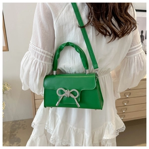 Detail der grünen Mini-Handtasche mit Strass-Schleife am Modell in Rückansicht