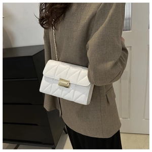 Detail shot of a white quilted crossbody bag with a gold rectangular metal clasp and chain