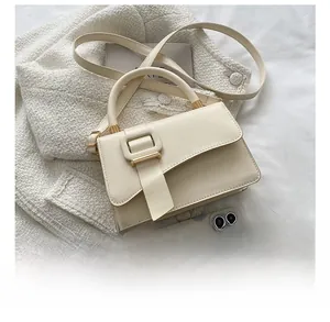 Size comparison of cream white crossbody bag next to a smartphone on tweed fabric