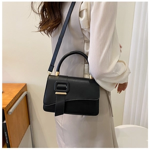 Close-up of a minimalist black faux leather shoulder bag with gold hardware and top handle
