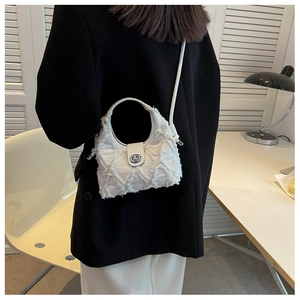 Détail du sac seau en toile matelassée blanche avec fermoir rotatif argenté et bandoulière