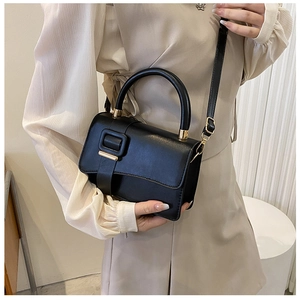 Detail of minimalist black PU leather handbag with a large decorative square buckle