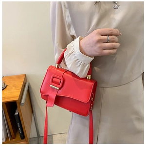 Detail of red vintage shoulder bag with large square buckle and gold metal accents