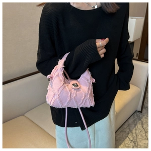 Détail du sac seau en denim rose avec fermoir rotatif en métal et bandoulière