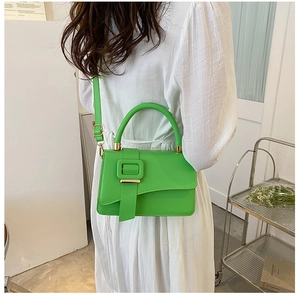 Detail of bright green polished leather handbag with crossbody strap and square buckle