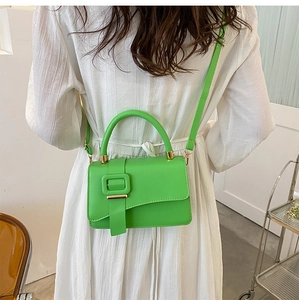 Detail view of vibrant green PU leather crossbody bag with top handle and gold hardware