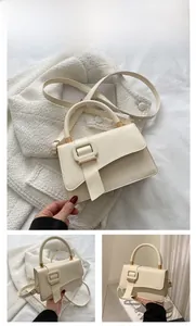 Detail view of cream leather shoulder bag featuring a gold buckle and asymmetric flap design
