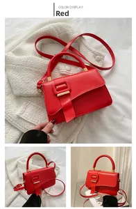 Macro view of bright red faux leather handbag featuring golden metal hardware and strap