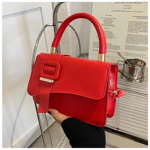 Close-up of bright red minimalist handbag with gold metal accents and square buckle