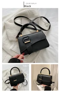 Detail view of black PU leather handbag with gold buckle and adjustable strap