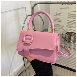 Detail of pink faux leather handbag with golden hardware and decorative buckle