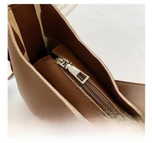 Close-up of matte silver zipper pull and premium brown leather texture on handbag