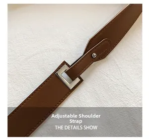 Detail of adjustable brown leather shoulder strap with silver metal buckle and stitching