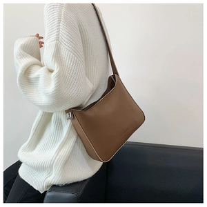 Detail view of brown hobo bag with silver buckle and logo on white knit sweater