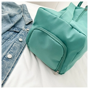 Close-up of mint green nylon travel bag featuring side zipper pocket and reinforced handle