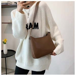 Mirror selfie showing the brown minimalist crossbody bag with wide shoulder strap details