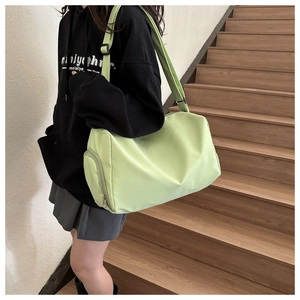 Detail of light green waterproof nylon tote bag showing the side zipper pocket and strap