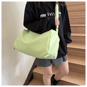 Detail of light green nylon boston bag with wide shoulder strap on a female model