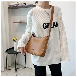 Detail showing the brown minimalist crossbody bag with refined texture and slim shoulder strap
