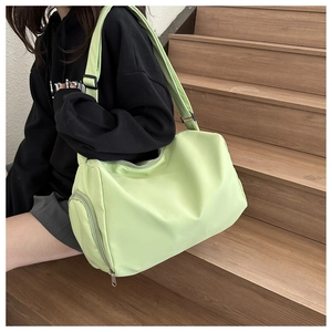Detailed side view of light green nylon duffel bag featuring wide strap and zipper pocket