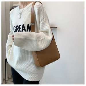 Detailed view of the brown leather shoulder bag featuring adjustable silver metal buckle